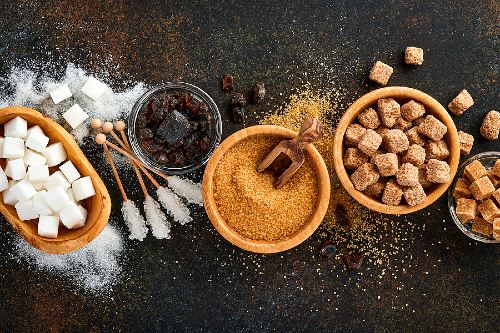 bowls of different types of sugar on a black background