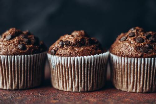 three chocolate pumpkin muffins arranged side-by-side with a dark background