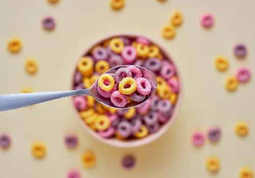 spoon being held above a bowl of cereal