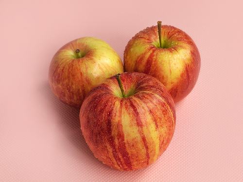 three apples on a pink background