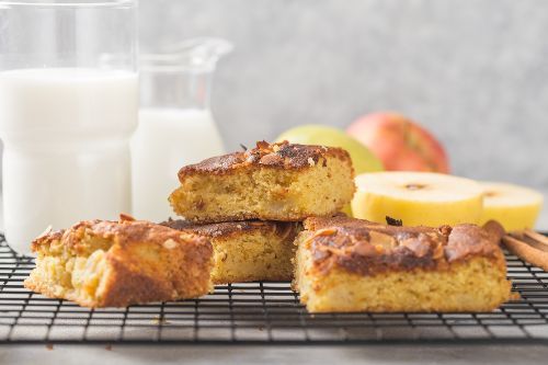 Cinnamon apple cake pieces with apples and milk in the background