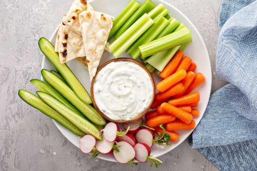 late of carrots, celery, pita bread, radishes with a bowl of white dip