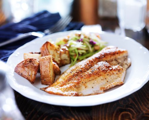 pan fried fish on a plate with potatoes and green vegetables