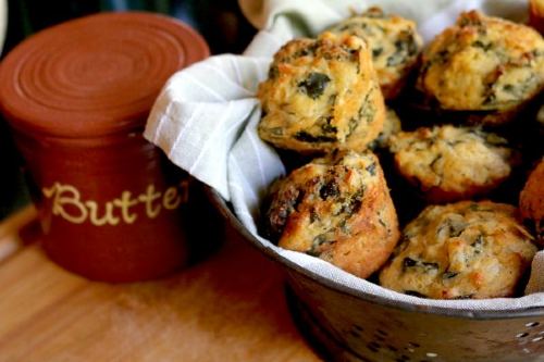 collard corn bread muffins in a cloth lined bowl next to a butter jar