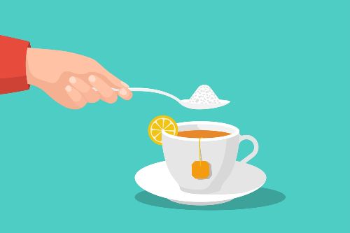white tea cup filled with tea and a lemon slice on the cup with a person's hand spooning in a teaspoon of sugar into the cup
