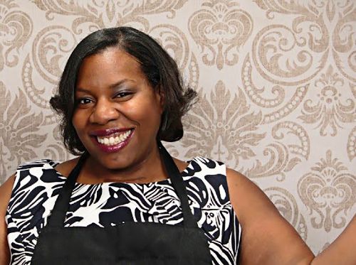 African American female chef wearing black apron and smiling