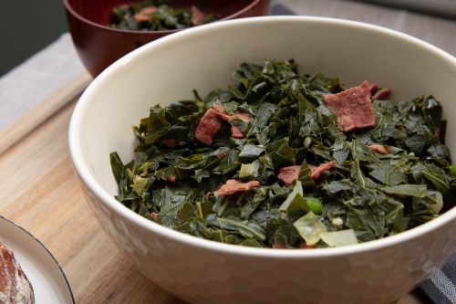 cooked collard greens with turkey bacon pieces inside white bowl