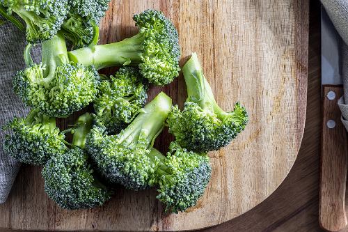 raw broccoli florets on a wooden cutting board