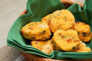 Cheesy Sweet Potato and Greens Biscuits in a basket lined with a green cloth