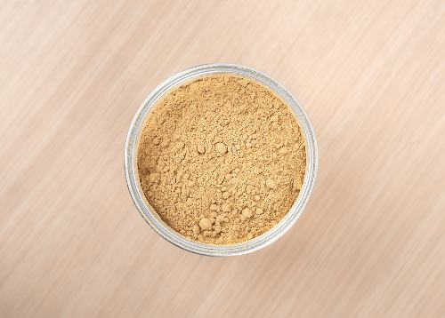 a small glass bowl of ground ginger sitting on a wooden surface 