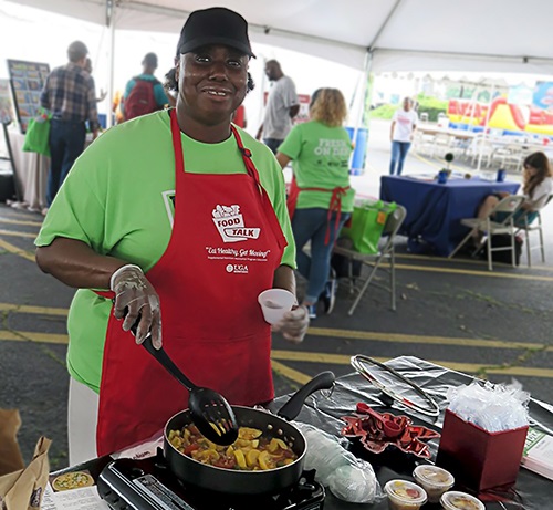 African American lady cooking squash in a skillet at a farmers market