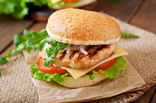 sesame seed bun with lettuce, tomato, cheese, grilled chicken between the buns