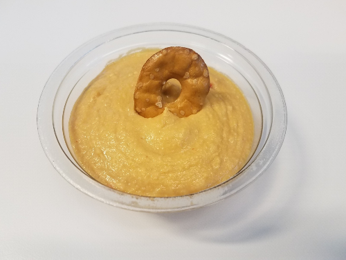 small glass bowl filled with hummus and a pretzel chip sticking in the hummus