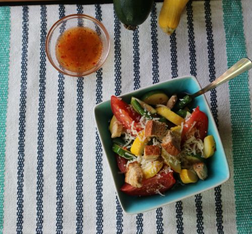 Summer salad in a bowl on a table covered with a striped table cloth