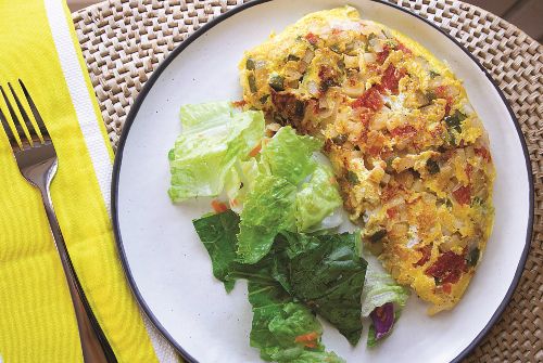 apple omelet and salad on a plate next to a yellow napkin and fork