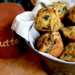 collard corn bread muffins in a cloth lined bowl next to a butter jar