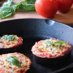 Photo shows three eggplant "pizzas" in a cast iron skillet