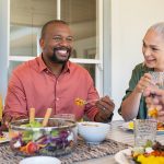 smiling friends enjoying dinner around table