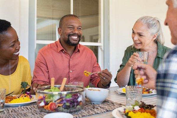 smiling friends enjoying dinner around table