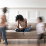 Exhausted mother on couch with hand on her forehead