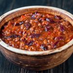 Bowl of chili con carne on a wooden table