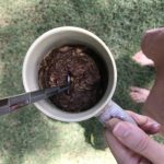 hand holding mug with chocolate zucchini cake outside