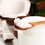 Coconut oil with fresh nut and palm leaves on background. Ripe coconut fruits