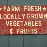Maroon wooden sign reading "Farm Fresh Locally Grown Vegetables & Fruits"