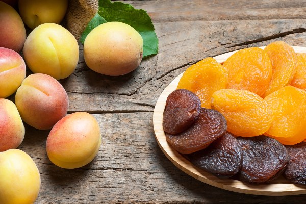 fresh and dried apricots on a wooden background