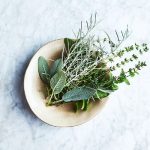 fresh herbs in a ceramic bowl on a marble surface