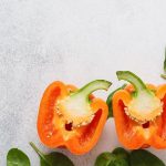 orange bell pepper that is cut in half on a gray countertop