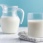 Glass and jug of milk on a blue background.