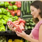 Woman deciding which vegetable to buy in grocery store