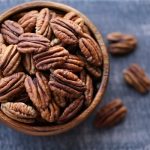 Pecan nut close-up in a round wooden cup on a black background