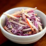 coleslaw in a small white bowl on a wooden tabletop