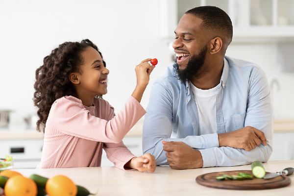 African american father and daughter eating veggies