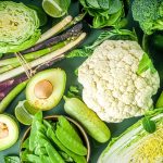 Assortment of fresh vegetables - broccoli, cauliflower, zucchini, cucumbers, asparagus, spinach, avocado, cabbage set on dark green background