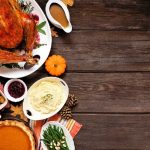 thanksgiving dinner dishes arranged on the left side of the photo with the rest of the photo appearing as a wooden background