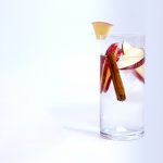Glass of water with cinnamon sticks and apple slices