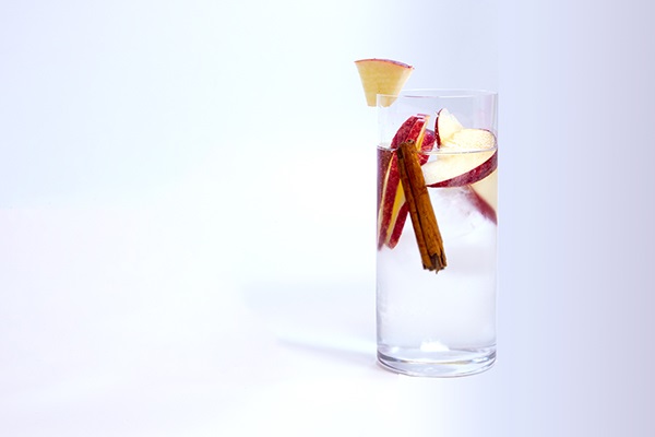 Glass of water with cinnamon sticks and apple slices