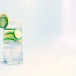 Glass of water with lemon slices on slices and cucumber