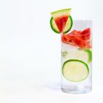 Glass of water with watermelon pieces and lime slices in the glass