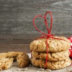 stack of cookies with a red ribbon tied around them next to a red and white checked napkin and a broken cookie