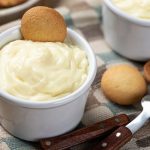 2 white custard dishes filled with vanilla custard and a vanilla wafer in each bowl with 2 vanilla wafers between the bowls