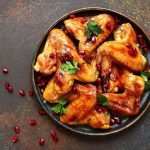 chicken wings covered with an orange glaze served on a black platter