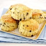5 scones with raisins on a serving dish on top of a blue folded dish towel