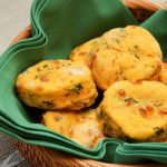 Cheesy Sweet Potato and Greens Biscuits in a basket lined with a green cloth