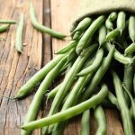 Green beans in a gunny sack spilling out on a wooden table