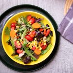 salad with tomato, lettuce, corn, and carrots in a bowl on a table