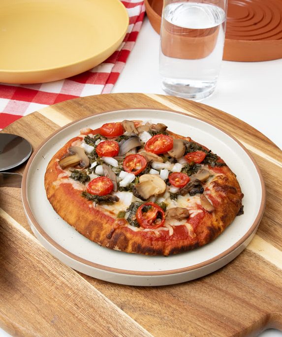 small pizza on a plate next to a pizza cutter